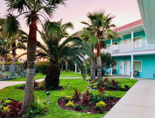 a resort with palm trees in front of a building at Days Inn by Wyndham Port Aransas TX in Port Aransas