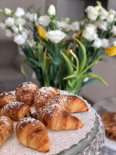 a plate of pastries on a table with a vase of flowers at Pietra Bianca Rooms in Pachino