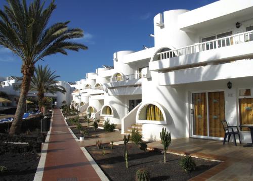 a white building with palm trees in front of it at Hotel Floresta in Puerto del Carmen