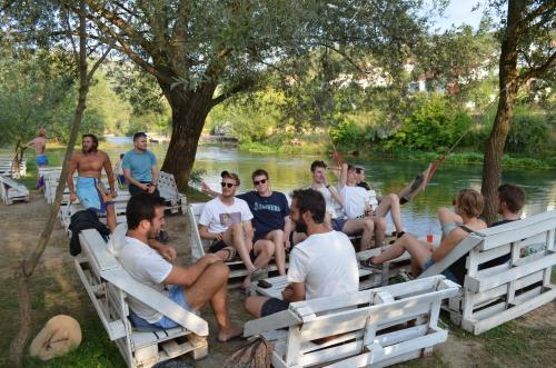 a group of people sitting on chairs by the water at Hostel Backpackers in Mostar