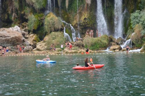 a group of people in kayaks in the water near a waterfall at Hostel Backpackers in Mostar