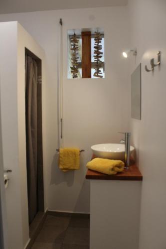 a white bathroom with a sink and a shower at Résidence Bois Flotté in Sainte-Anne