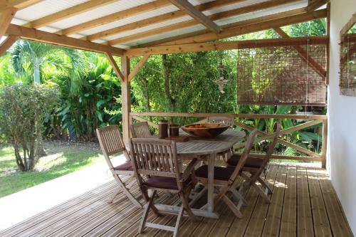 a wooden table and chairs on a wooden deck at Résidence Bois Flotté in Sainte-Anne