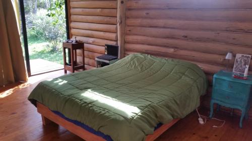 1 dormitorio con 1 cama y pared de madera en Chalet Los Troncos, en Sauce de Portezuelo
