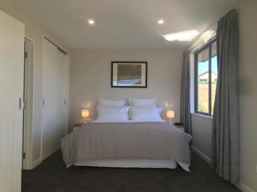 a bedroom with a bed with white pillows and a window at Minaret Ridge Retreat in Wanaka