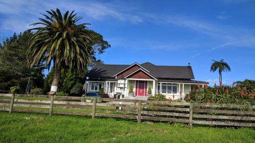 a house with a fence and a palm tree at HomeWell in Tauranga