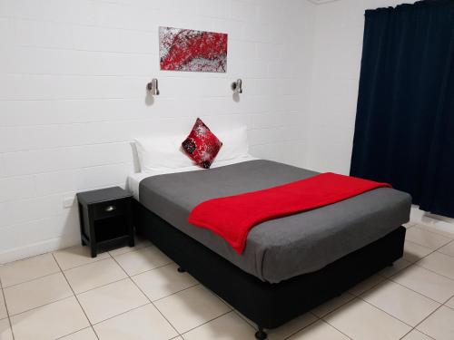 a bedroom with a bed with a red blanket on it at Capricorn Hotel in Blackwater