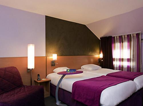 a hotel room with two beds and a chair at ibis Styles Bourg-en-Bresse Centre in Bourg-en-Bresse