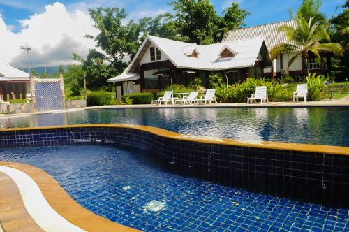 a swimming pool with chairs and a house at Pai Iyara Resort in Pai