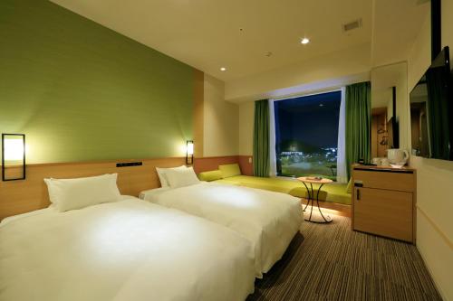 a hotel room with two beds and a window at Candeo Hotels Nara Kashihara in Kashihara