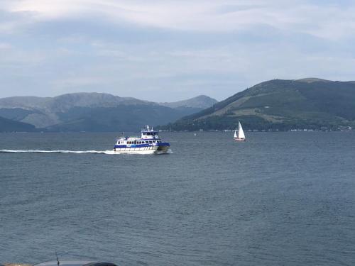 a boat on a large body of water with a sailboat at The Wee Ludging Cottage, Rashfield, by Dunoon in Dunoon