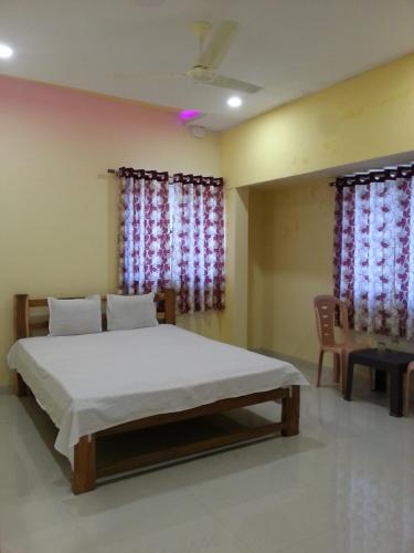 a bedroom with a bed and a chair and windows at Maharaja Home Stay Panhala in Panhāla