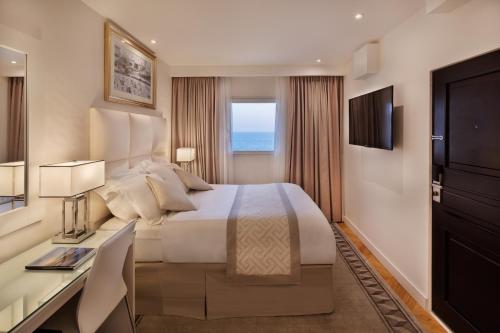 a hotel room with a bed and a desk and a window at Orchid Tel Aviv in Tel Aviv