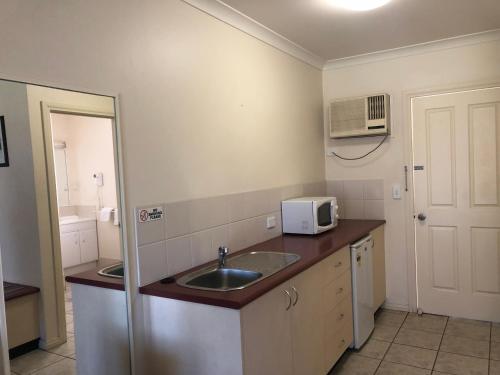 a small kitchen with a sink and a microwave at Outback Quarters Motel Hay and Restaurant in Hay