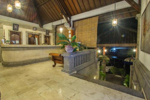 a lobby with a bar with a table and a plant at Tamukami Hotel in Sanur