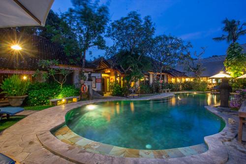 a swimming pool in a backyard at night at Tamukami Hotel in Sanur