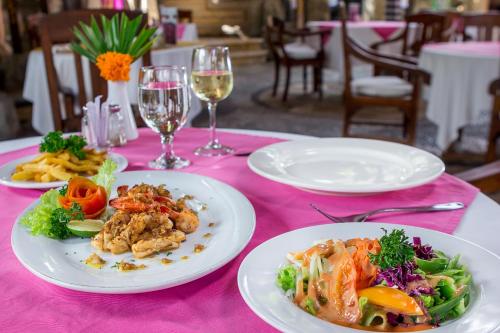 a pink table with plates of food and glasses of wine at Tamukami Hotel in Sanur