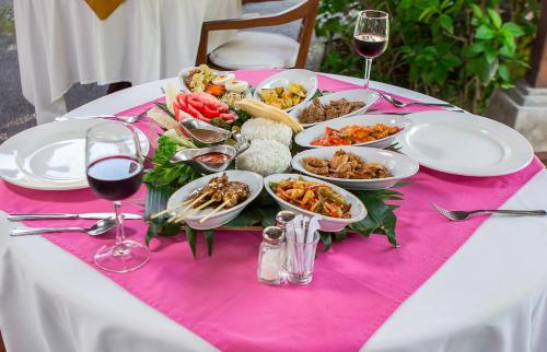 a table with plates of food and glasses of wine at Tamukami Hotel in Sanur
