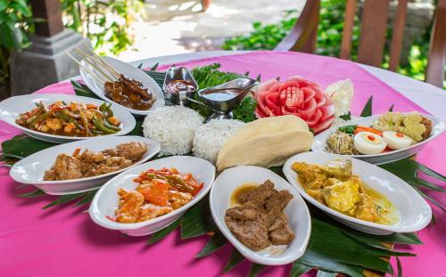 a table with plates of food on a pink table at Tamukami Hotel in Sanur