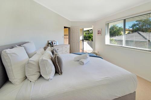 um quarto branco com uma grande cama branca com almofadas em Advance Place em Sunrise Beach