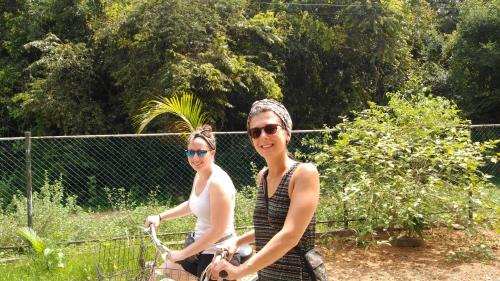 two women are riding bikes in front of a fence at Priyanna Guest, Forest view in Polonnaruwa