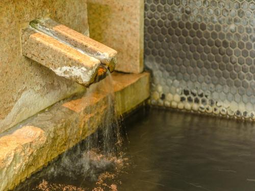 a stream of water coming out of the side of a wall at Ryokan Fukinoya in Yufuin