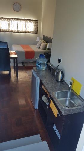 una cocina con fregadero y una cama en una habitación en Beachway Guesthouse, en Port Elizabeth