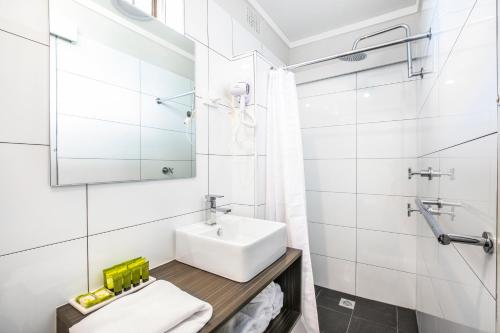 a white bathroom with a sink and a mirror at Nightcap at Jamison Hotel in Penrith