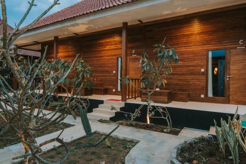 a house with wooden walls and a courtyard with plants at Devadav Hostel (Bunk Bed) Nusa Lembongan in Nusa Lembongan