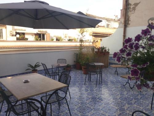 un patio con tavoli, sedie e ombrellone di Ad Hoc Rooms a Palermo