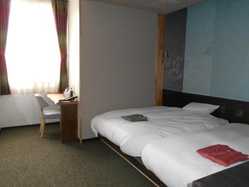 a hotel room with two beds and a desk at Kojohama Onsen Hotel in Shiraoi