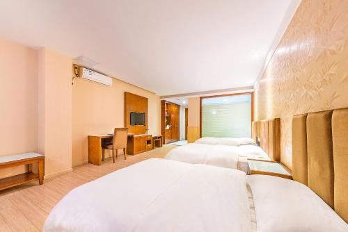 a hotel room with four beds and a desk at Kaiserdom Hotel Baiyun Airport-24-hour Airport-Free shuttle bus in Huadu