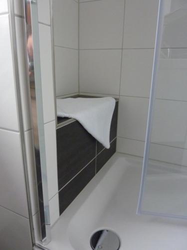 a shower stall with a white towel on a counter at Gästehaus Erle in Memmingen