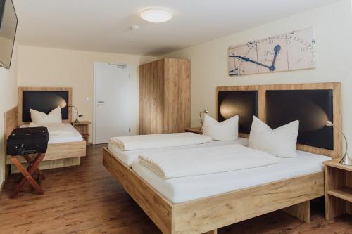 twee bedden in een kamer met een klok aan de muur bij Gästehaus Hötzl in Galgweis