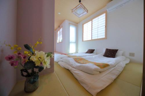 - une chambre avec 2 lits et un vase de fleurs dans l'établissement Kyo Machiya Ryokan Yuan, à Kyoto