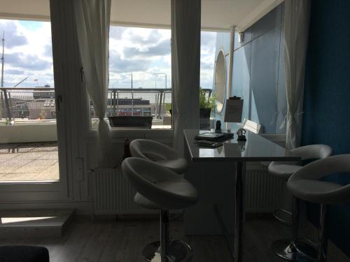 ブレーマーハーフェンにあるhavenBlicke - großzügige Terrasse mit Blick auf die Weserのデスク、椅子、窓が備わる客室です。