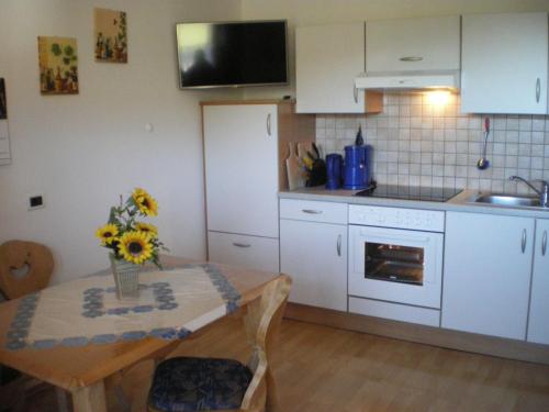 una cocina con una mesa con un jarrón de flores. en Ferienwohnung Winklerhof en Maranza