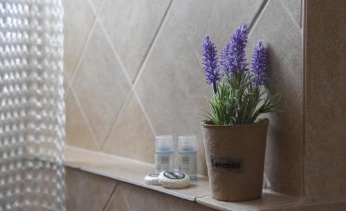 a vase with purple flowers on a shelf in a bathroom at Hotel Διεθνές in Zacharo