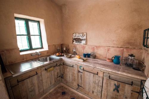 kuchnia z drewnianymi szafkami, umywalką i oknem w obiekcie Beit Al Fannan w mieście Ţabaqat Faḩl