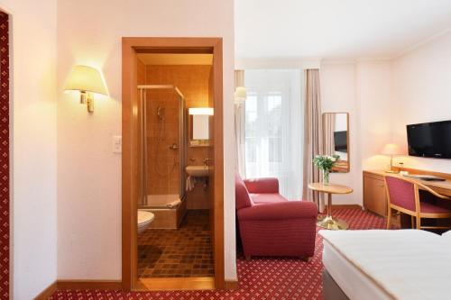 a hotel room with a red chair and a bathroom at Elite in Lausanne