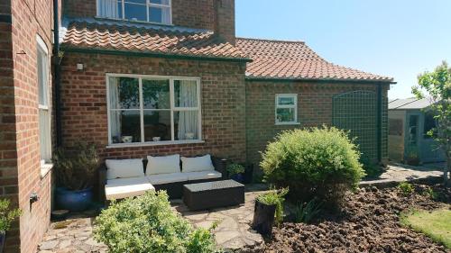 a brick house with a couch in a garden at Southwold Bridlington in Bridlington
