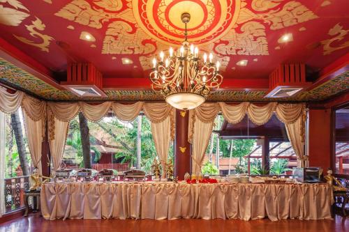 Royal Phawadee Village Patong - 2 Minutes walk to the beach في شاطيء باتونغ: طاولة في غرفة مع ثريا