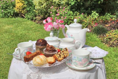 a table with a plate of pastries and tea cups at Mellowvean in St. Agnes