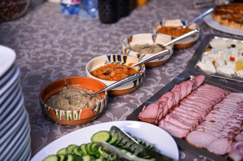 a table topped with plates of food with meat and dips at Cabana Bistrita in Durau