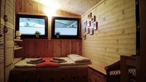 a room with a bed in a wooden room with two windows at Bory Tucholskie Domek in Skorzenno