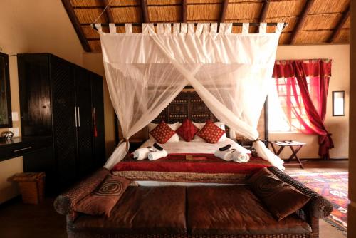 a bedroom with a canopy bed with stuffed animals on it at Khaya Umdani Guest Houses in Marloth Park