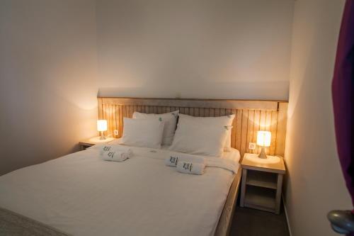 a bedroom with a white bed with two lamps at Apartments Grifone Lux in Herceg-Novi