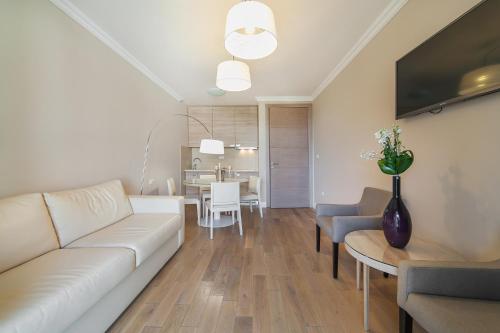 a living room with a white couch and a dining room at Apartments Grifone Lux in Herceg-Novi