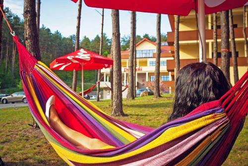 a woman laying in a hammock in a park at Hotel Drohicki in Drohiczyn nad Bugiem