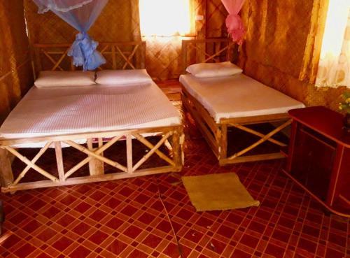 two beds are sitting in a room with a floor at Scoop Cabana Kitesurfing in Kalpitiya